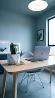 Minimalist home office with wooden desk, laptop, cactus in marble pot, and modern chair in soft blue interior lighting.