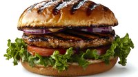 Juicy grilled beef burger with fresh lettuce, tomato, red onion rings on golden brioche bun against white background, appetizing close up view.