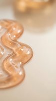 Golden transparent serum drops with bubbles on neutral background for skincare and cosmetic product photography applications.