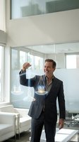 Confident middle-aged Caucasian businessman in dark suit holding glowing digital scales of justice in modern office interior for legal technology concepts.