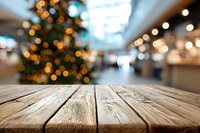 Wooden table with blurred Christmas tree and shopping mall background, festive holiday atmosphere for product display.