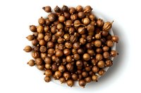 Dried coriander seeds in round pile isolated on white background, macro view of whole brown spice for cooking and seasoning food.