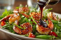 Grilled shrimp salad with fresh greens and red bell peppers drizzled with balsamic glaze, served as gourmet appetizer for restaurant menu.