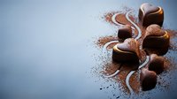 Chocolate truffles dusted with cocoa powder arranged on light blue surface with decorative cocoa swirls, ideal for bakery, confectionery, and food photography projects.