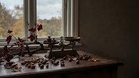 Vintage brass balance scale with coffee beans on wooden table by window with autumn foliage, creating warm atmospheric lighting for kitchen decor concepts.