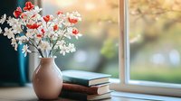 White and red flowers in ceramic vase on windowsill with stacked books, soft natural daylight creating cozy home atmosphere with bokeh background effect.