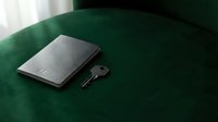 Closed laptop and key on green velvet surface, symbolizing security, access, and data protection for technology and business concepts.