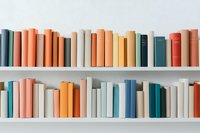 Books arranged in rows on white shelves displaying harmonious color palette of coral, teal, yellow and white spines, creating minimalist aesthetic for home decor and design.