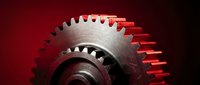 Close-up of metallic gear wheel with sharp teeth on dark red background. Industrial machinery component for engineering and manufacturing concepts.