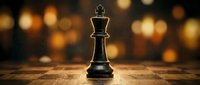 Black chess king piece standing alone on wooden chessboard with warm golden bokeh lights background creating strategic leadership concept for business.