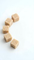 Brown sugar cubes arranged in curved line on white background, suitable for food photography, culinary design, beverage styling, and sweetener product advertising.