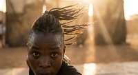 Young African woman with dreadlocks in golden sunlight, natural beauty portrait with warm lighting and authentic expression for lifestyle content.
