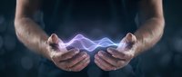 Male hands cupping glowing purple and blue energy waves on dark background. Concept for healing, magic, power, technology and spiritual energy.