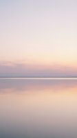 Serene dawn seascape with soft pastel sky reflecting on calm water, creating a tranquil minimalist scene for wellness and meditation projects.