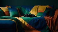 Cozy bedroom interior with colorful bedding and pillows in warm lighting creating comfortable sleeping atmosphere for home decor and lifestyle concepts.