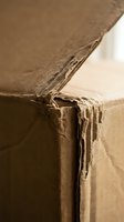 Damaged brown cardboard box with torn edges and worn corners showing wear from shipping and handling in sepia tone.