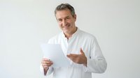 Middle-aged Caucasian male professional in white shirt holding blank document, pointing at paper with confident gesture against white background.