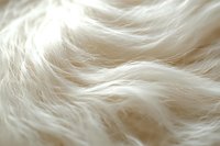 Soft white fluffy fur texture with gentle waves and natural light creating subtle shadows, ideal for luxury product backgrounds.