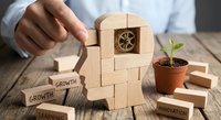 Business professional assembling wooden puzzle head with gear brain symbolizing strategic thinking, personal development and innovation mindset for corporate growth.