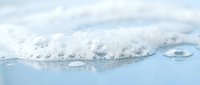 Snow-covered mountain peaks rising above clouds in serene winter landscape with soft blue sky and peaceful atmospheric conditions for nature photography.