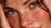 Young Caucasian woman with freckles and wet skin touching face in skincare routine concept for natural beauty and self-care advertising campaigns.