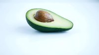 Fresh ripe avocado half with pit on white background isolated for healthy cooking and nutrition design projects.