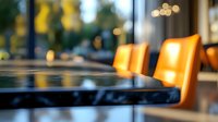 Modern restaurant interior with empty orange chairs and dark tables illuminated by warm ambient lighting, creating atmospheric dining environment with bokeh effect.