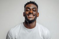 Happy young African American man with beard smiling broadly in white t-shirt against gray background for lifestyle and portrait photography.