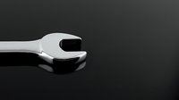 Chrome wrench tool on dark surface with copy space for mechanical repair and maintenance projects.