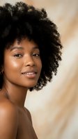 Young African American woman with natural curly afro hair smiling confidently, glowing skin and warm lighting for beauty and skincare campaigns.