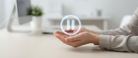 Professional businesswoman holding glowing pause button symbol in modern office workspace representing work-life balance and time management concepts.