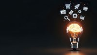 Glowing light bulb with brain filament and floating business icons representing innovation, creativity and entrepreneurship on dark background.