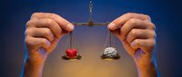 Hands protecting scales of justice with heart and brain, symbolizing balance between emotion and logic in decision making for legal concepts.