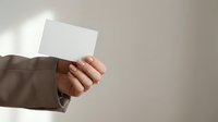 Professional businessperson hand holding blank white business card with copy space for corporate branding and contact information design.
