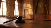 Wooden gavel on judge desk in elegant courtroom with warm lighting and classic interior design for legal proceedings and justice concepts.