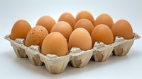 Fresh brown chicken eggs arranged in cardboard carton container on white background, natural organic food concept for healthy protein source.