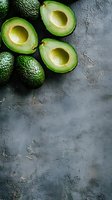 Fresh ripe avocados, whole and halved showing creamy flesh on dark concrete background with copy space. Food photography layout for healthy eating.