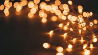 Warm golden string lights creating magical bokeh effect against dark background for holiday decorations and festive atmosphere design projects.
