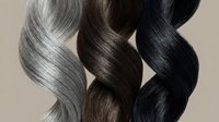 Three twisted hair strands in silver gray, brown and black colors showing natural texture and shine on neutral background for beauty salon concepts.