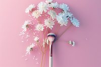 Makeup brush with white chrysanthemum flowers and scattered petals on pink background, creating delicate beauty composition for cosmetics and beauty industry.