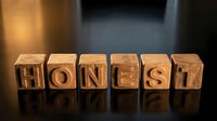 Wooden letter blocks spelling HONEST on a reflective dark surface with warm dramatic lighting, symbolizing integrity and trust.