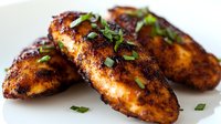 Grilled chicken breast with herbs and spices on white plate. Juicy barbecue meat with fresh green garnish for restaurant menu and cooking recipes.