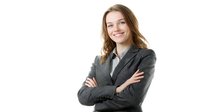 Young Caucasian businesswoman in grey suit jacket with confident smile and crossed arms against white background, professional corporate portrait for business marketing.