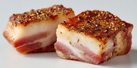 Crispy roasted pork belly slices with golden crackling skin and tender meat layers, perfect for culinary photography and food marketing materials.