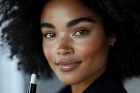 Young African American woman applying makeup with brush, natural beauty routine, skincare and cosmetics for daily self-care and confidence enhancement.