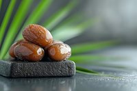 Fresh dates fruit arranged on dark stone surface with tropical palm leaves creating natural spa wellness atmosphere for healthy eating concepts.