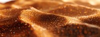 Golden flowing fabric with sparkling glitter particles creates luxurious textile waves. Shimmering material with bokeh light effects for elegant backgrounds.