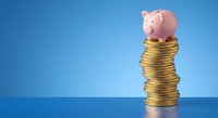 Pink piggy bank sitting on top of tall stack of golden coins against blue background representing savings growth and financial planning concepts.