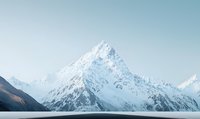 Majestic snow-covered mountain peak rising against clear blue sky, dramatic alpine landscape with pristine white slopes and rugged terrain in wilderness setting.