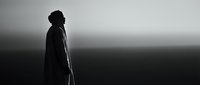 Silhouette of person with walking stick against dramatic sky. Contemplative figure in misty atmospheric landscape for wellness and journey concepts.